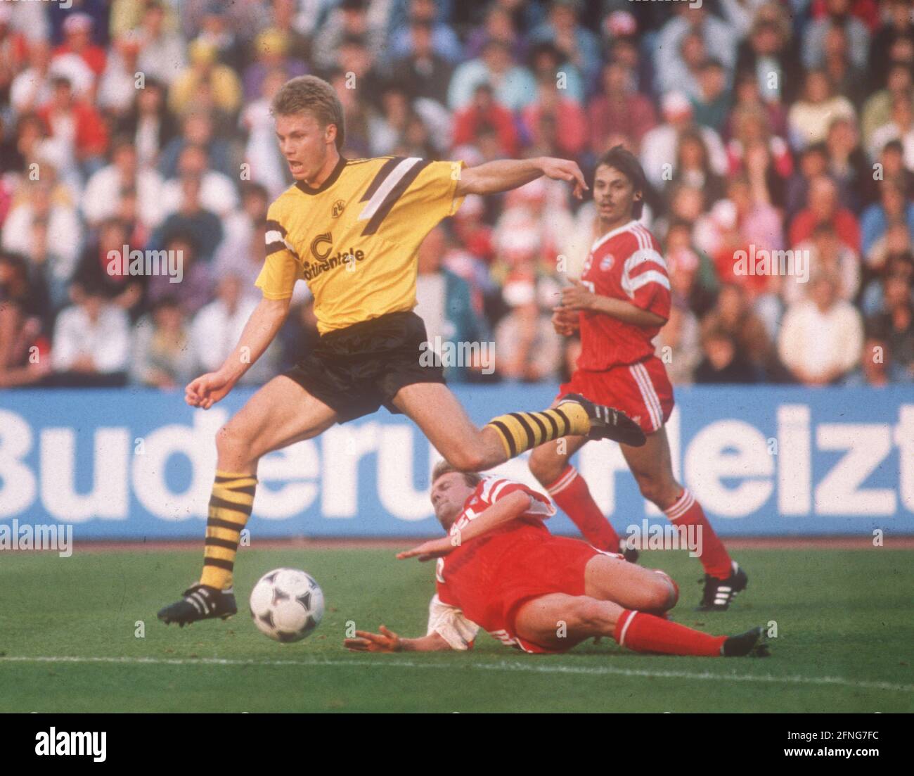 FC Bayern München - Borussia Dortmund 3:0/12.05.1990. Thomas Helmer (BVB) springt über Hans Dorfner. Hinten: Olaf Thon (beide FCB). [Automatisierte Übersetzung] Stockfoto