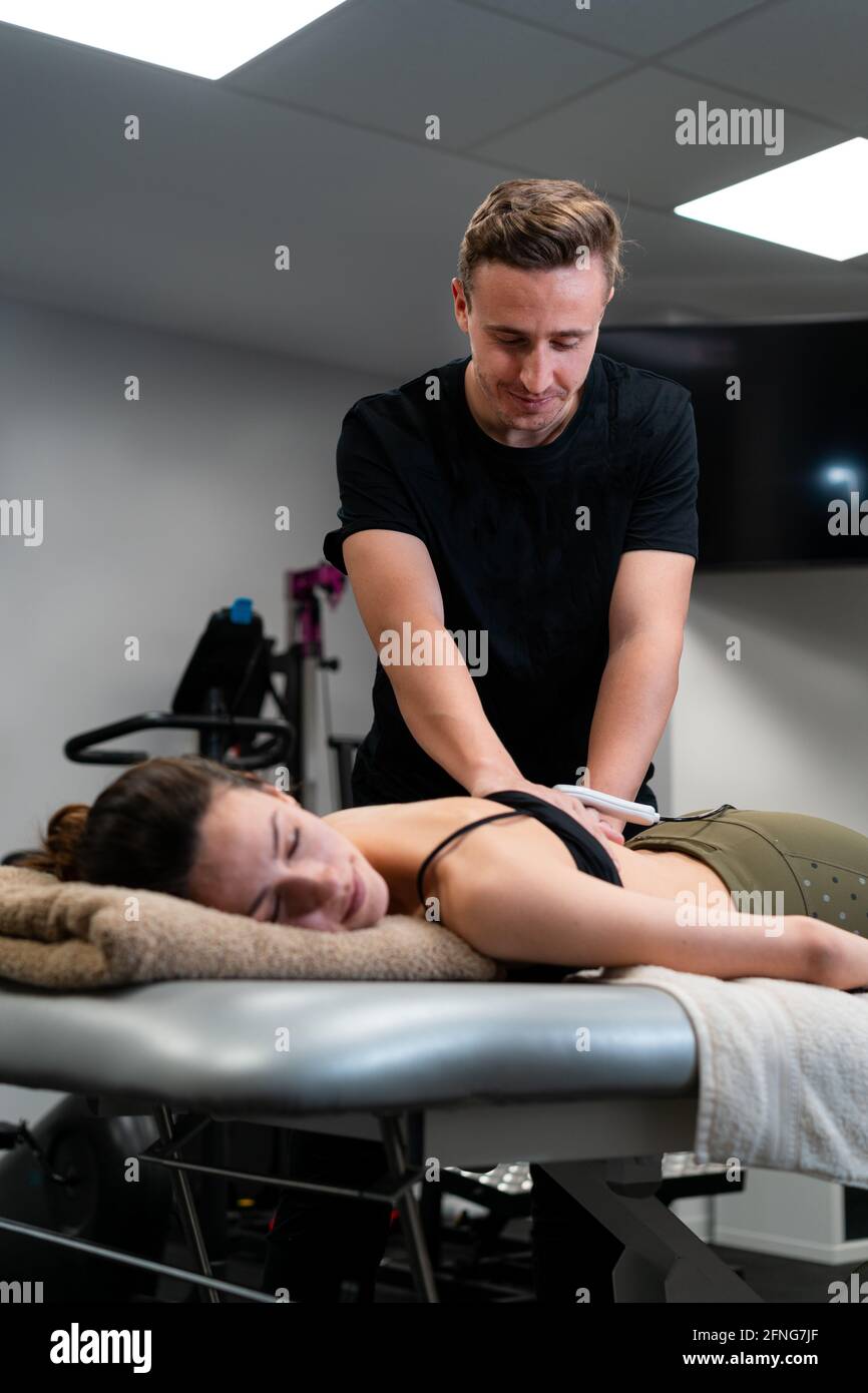 Männlicher Physiotherapeut, der während der Behandlung Laser auf die Rückenhaut des Weiblichen anwendet Medizinische Behandlung im Krankenhaus Stockfoto