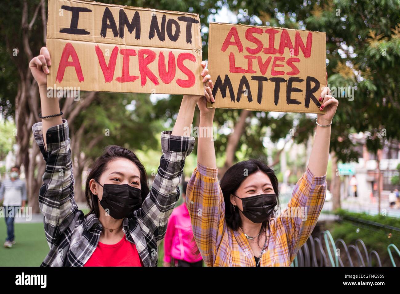 Ethnische Frauen in Masken mit Plakaten, die gegen Rassismus in protestieren Stadtstraße und Blick weg Stockfoto