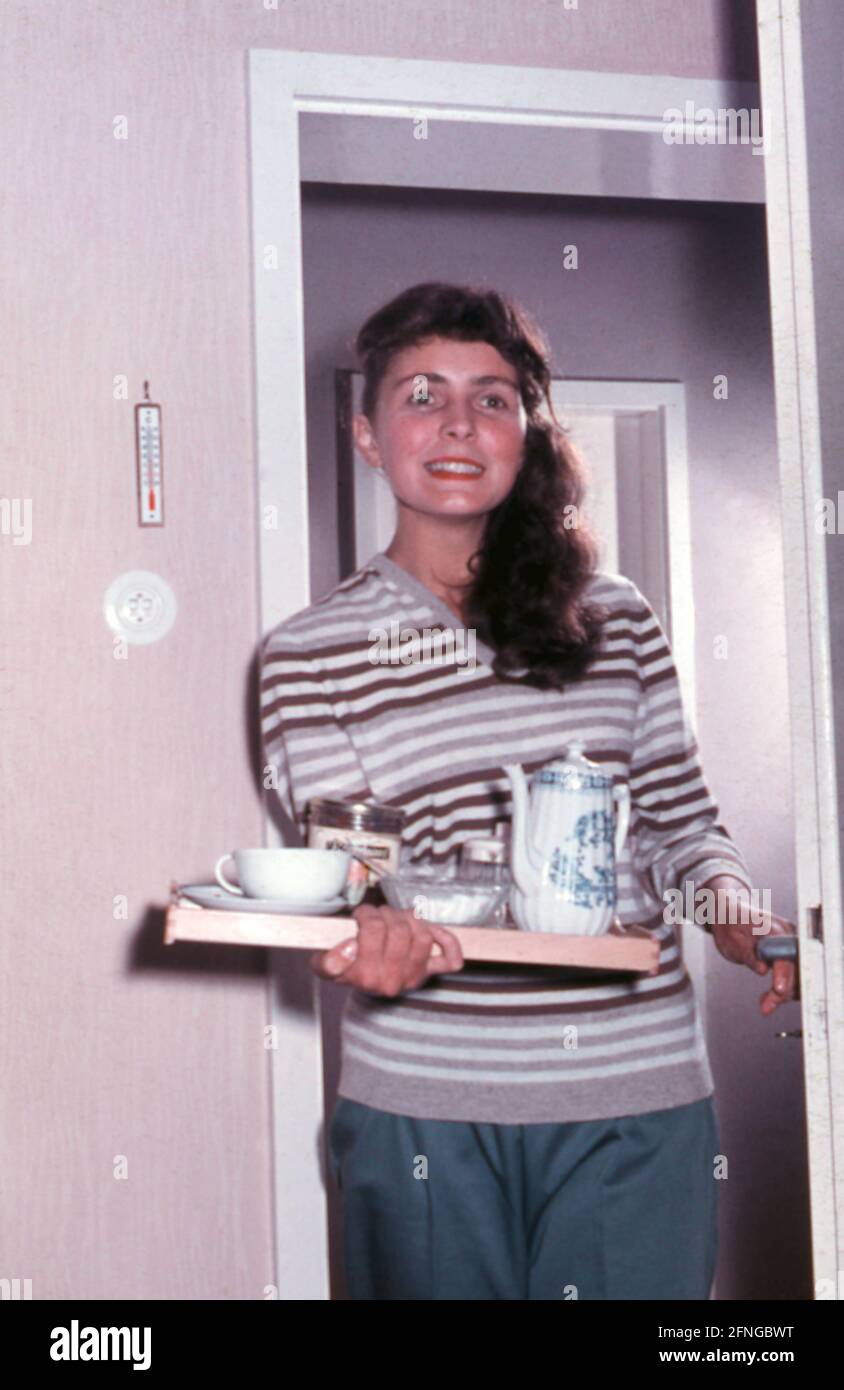 Junge Frau tritt in einen Raum mit einem vollen Tablett, 50er Jahre  [automatisierte Übersetzung] Stockfotografie - Alamy