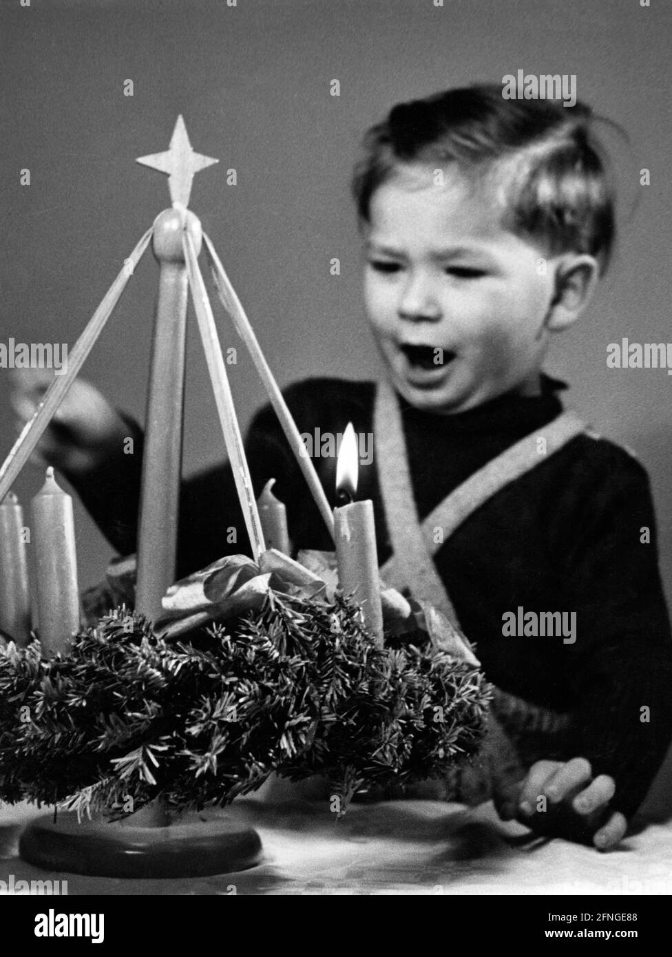 Ein kleiner Junge blickt begeistert auf einen Adventskranz, 40er Jahre [maschinelle Übersetzung] Stockfoto