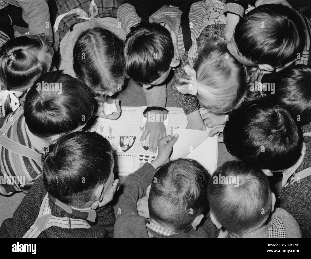 Kinder, die sich über ein illustriertes Kinderbuch mit einer Geschichte aus dem Orient beugen, 50er Jahre [automatisierte Übersetzung] Stockfoto