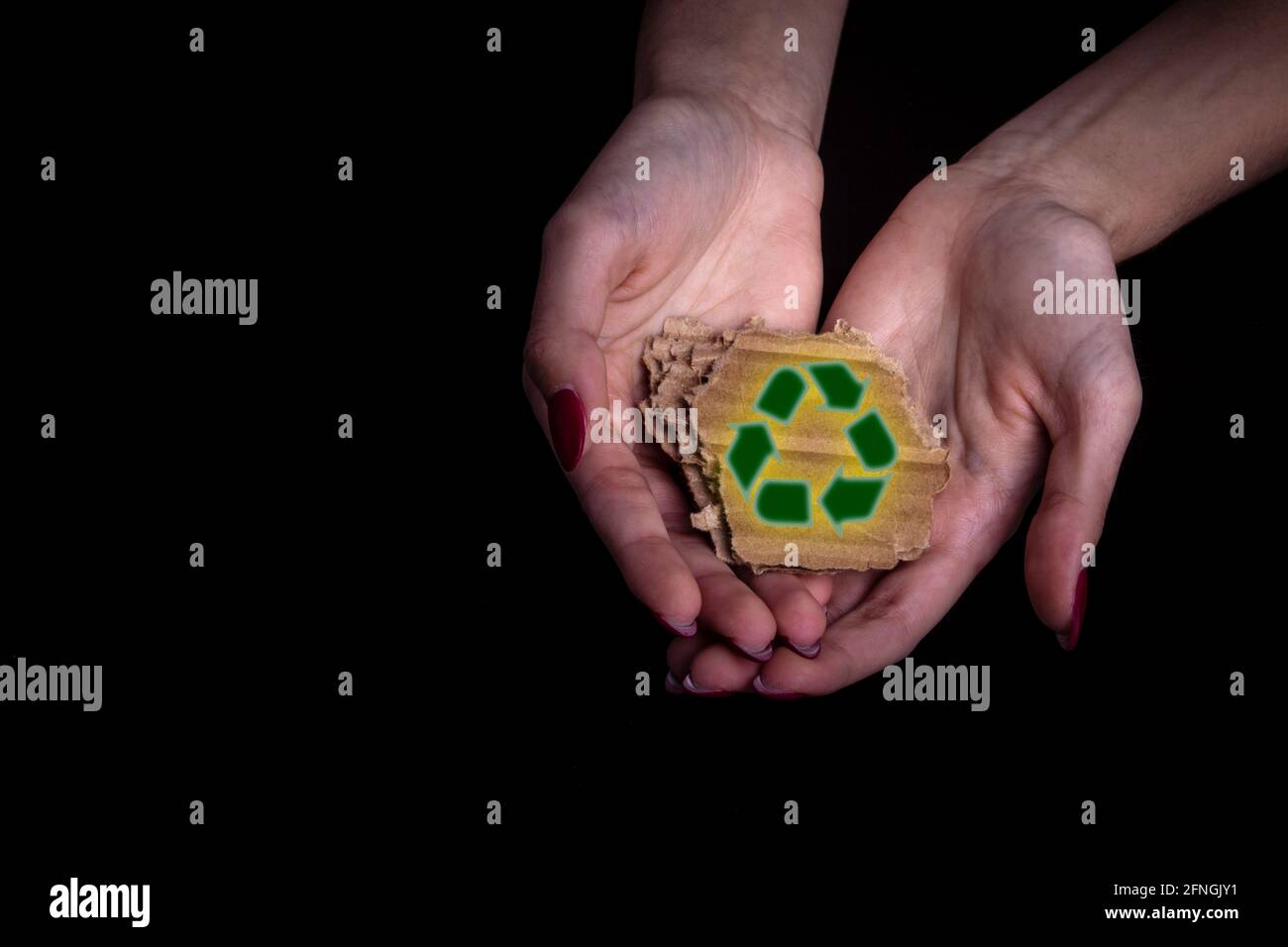 Frau Hand hält ein Stück Karton mit Recycling-Zeichen - Platz kopieren und schwarzer Hintergrund Stockfoto