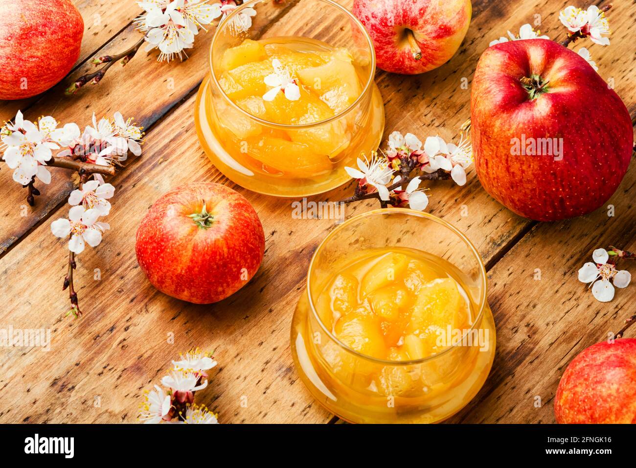 Apfelmarmelade im Glas und frische Äpfel auf rustikal Holzhintergrund Stockfoto