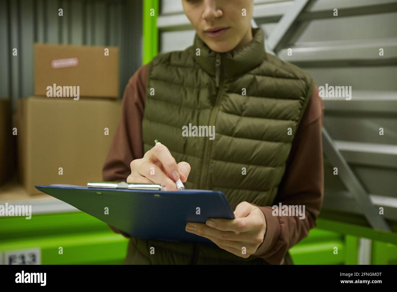 Nahaufnahme einer Frau, die während ihrer Arbeit in der Zwischenablage schreibt Lager Stockfoto