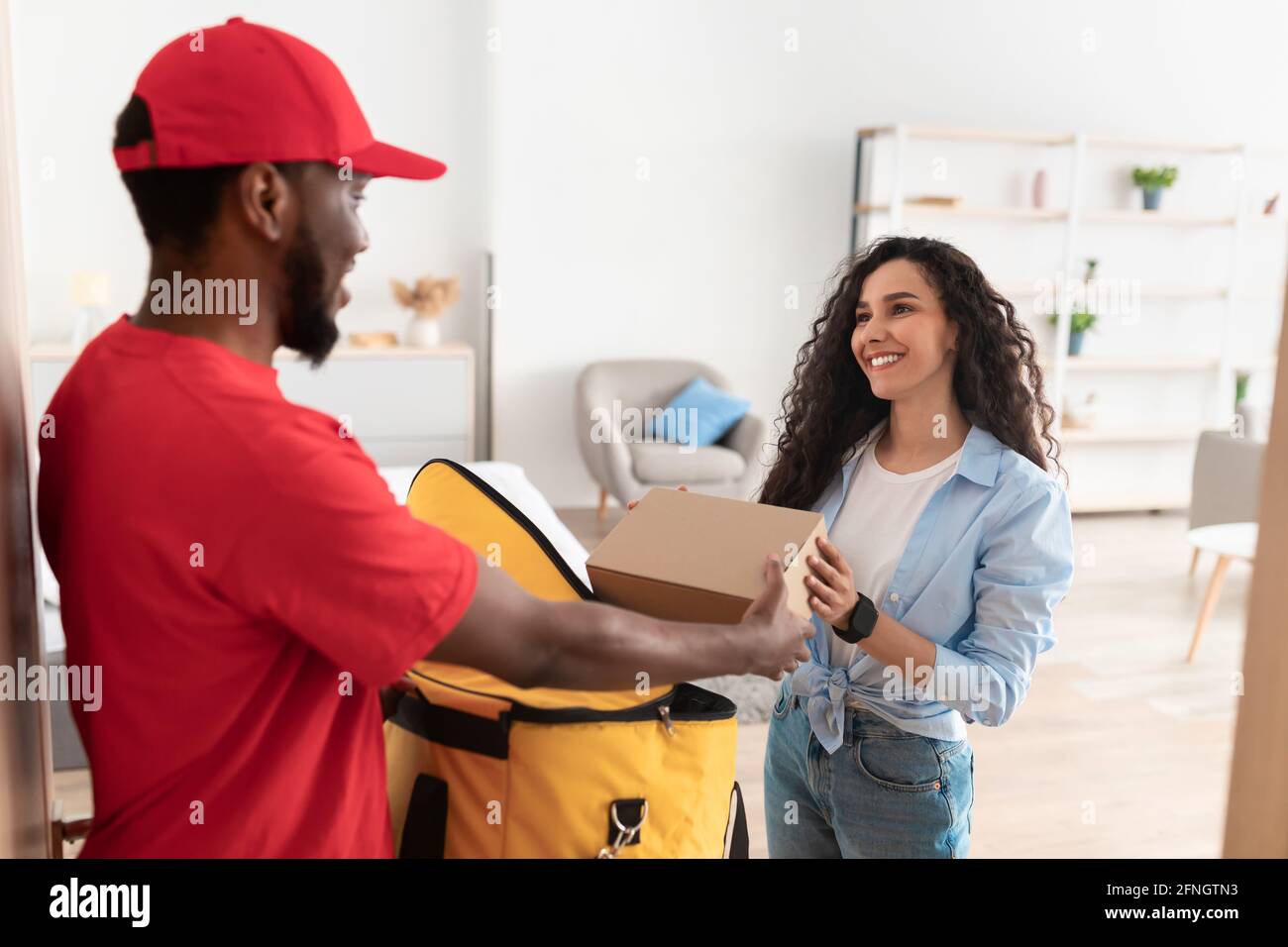 Schwarzer Lieferer nimmt die Box aus dem Thermorucksack Stockfoto