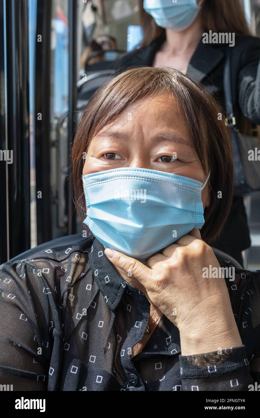 Reife asiatische Frau trägt eine Maske auf einem Bus: Selektiver Fokus. Sicherheit und neues Konzept der Regeln für den öffentlichen Verkehr. Stockfoto