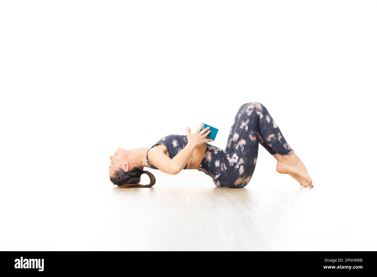 Junge sportliche attraktive Frau im leuchtend weißen Yoga-Studio, Stretching und Entspannung während erholsamem Yoga mit Gadget. Gesunder, aktiver Lebensstil Stockfoto