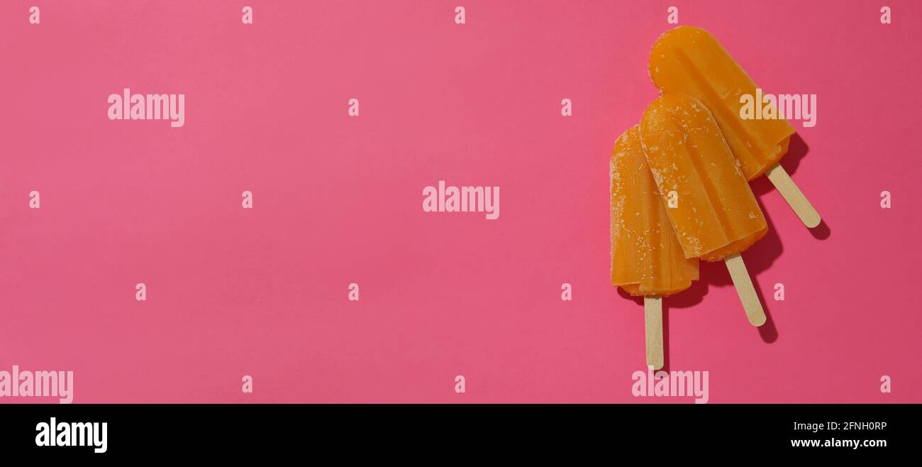 Mango- oder Karamell-Eis-Sticks auf rosa Hintergrund Stockfoto