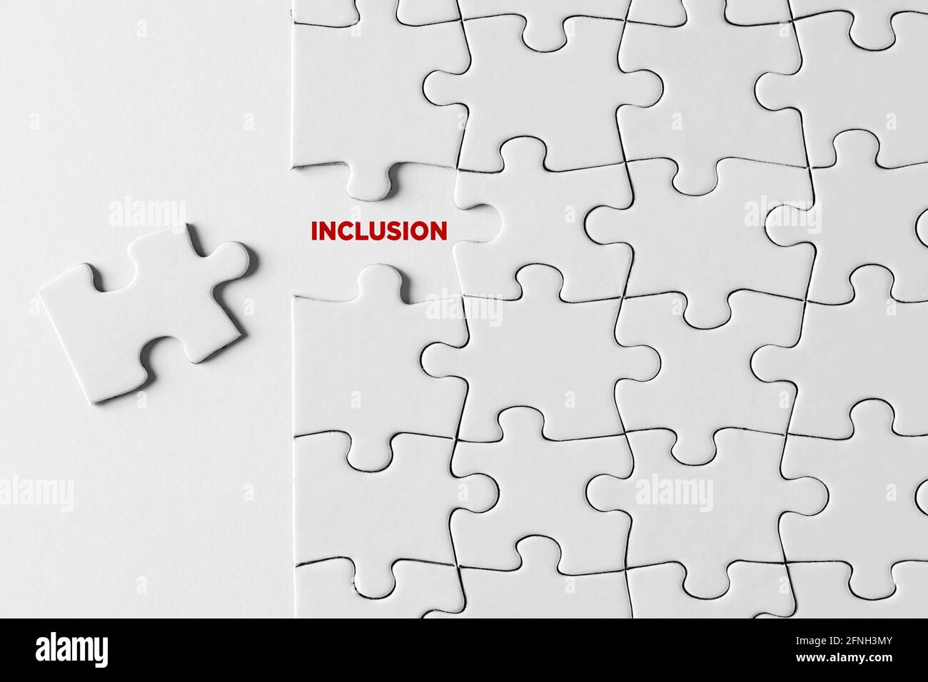 Inklusion, Integration und Zusammengehörigkeitskonzept. Das Wort Inklusion auf fehlendem Puzzleteil auf weißem Hintergrund geschrieben. Stockfoto