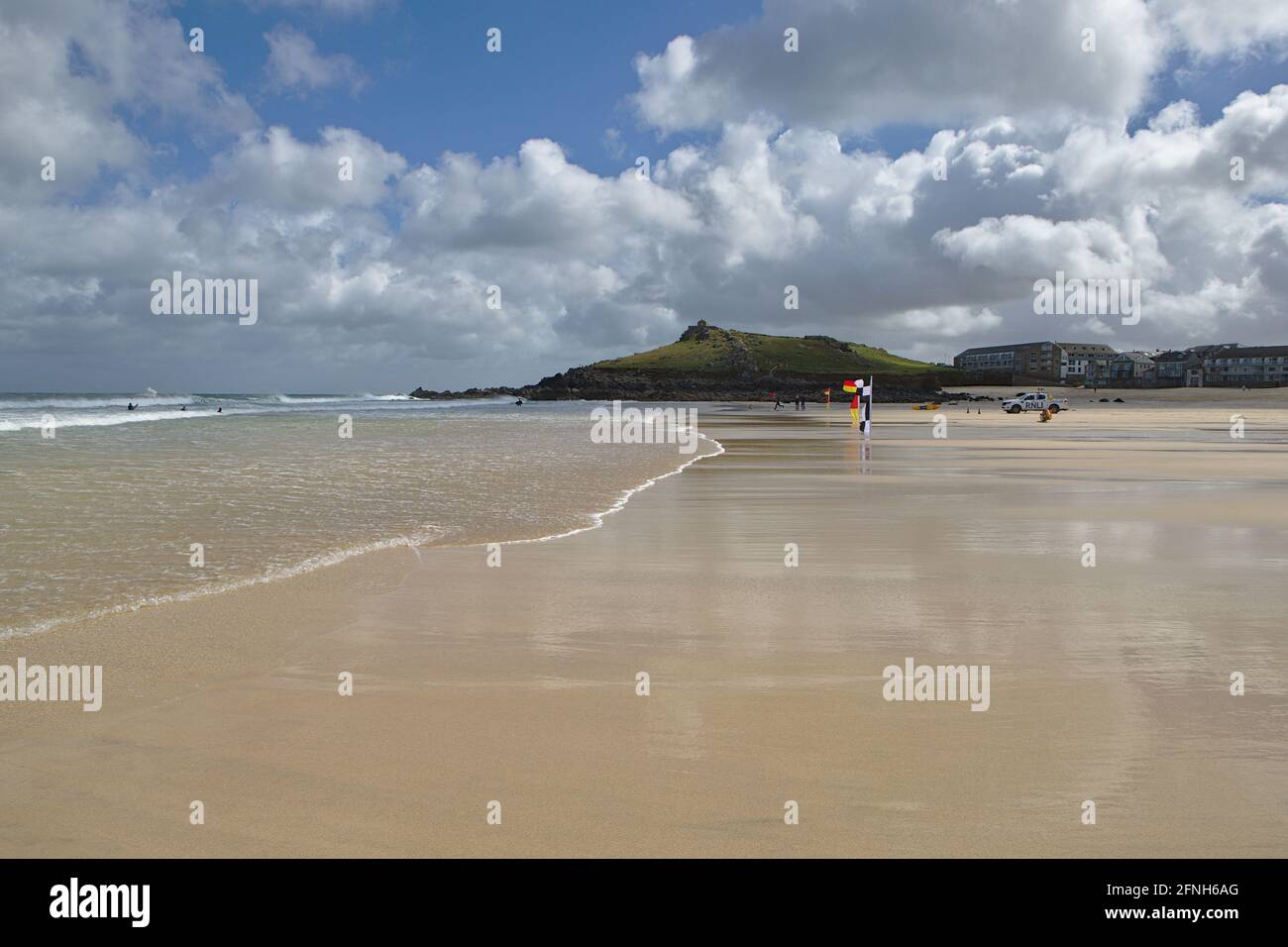 Glatter, flacher, nasser Sand bei Ebbe am Strand von Porthmeor Mit Surfflaggen Stockfoto