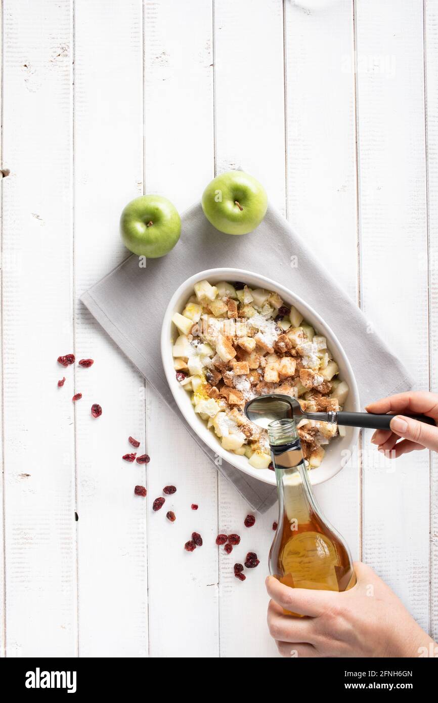 Rum in die Füllung für den Apfelstrudel, bestehend aus Äpfeln, Rosinen, geriebener Zitronenschale, Maismehl, Zimt, Geriebene Muskatnuss und Vanillepow Stockfoto