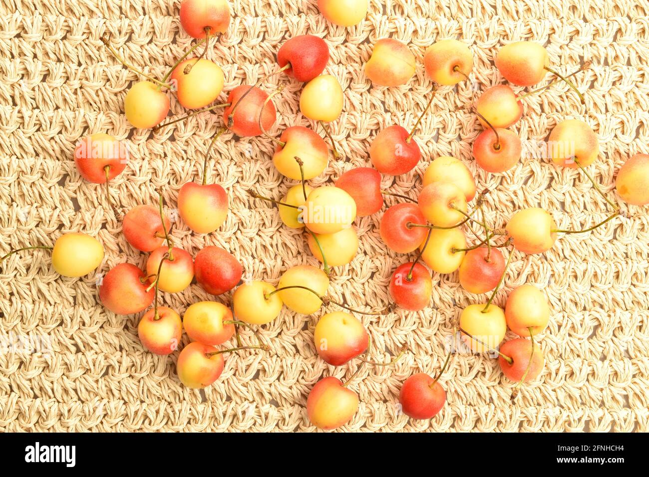 Reife gelbe Süßkirsche, Nahaufnahme, auf Strohmatte, Draufsicht. Stockfoto