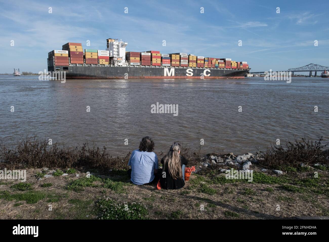 Die Menschen beobachten, wie ein riesiges MSC-Containerschiff mit globaler Ladung auf dem Mississippi River in der Nähe von New Orleans, Louisiana, vorbeifährt. Stockfoto