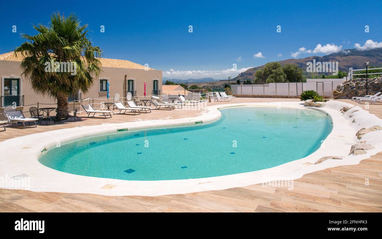 Scopello, Trapani, Sizilien, Italien. Blick über den malerischen Swimmingpool in den Gärten des Hotels Baglio di Scopello, Monte Inici im Hintergrund. Stockfoto