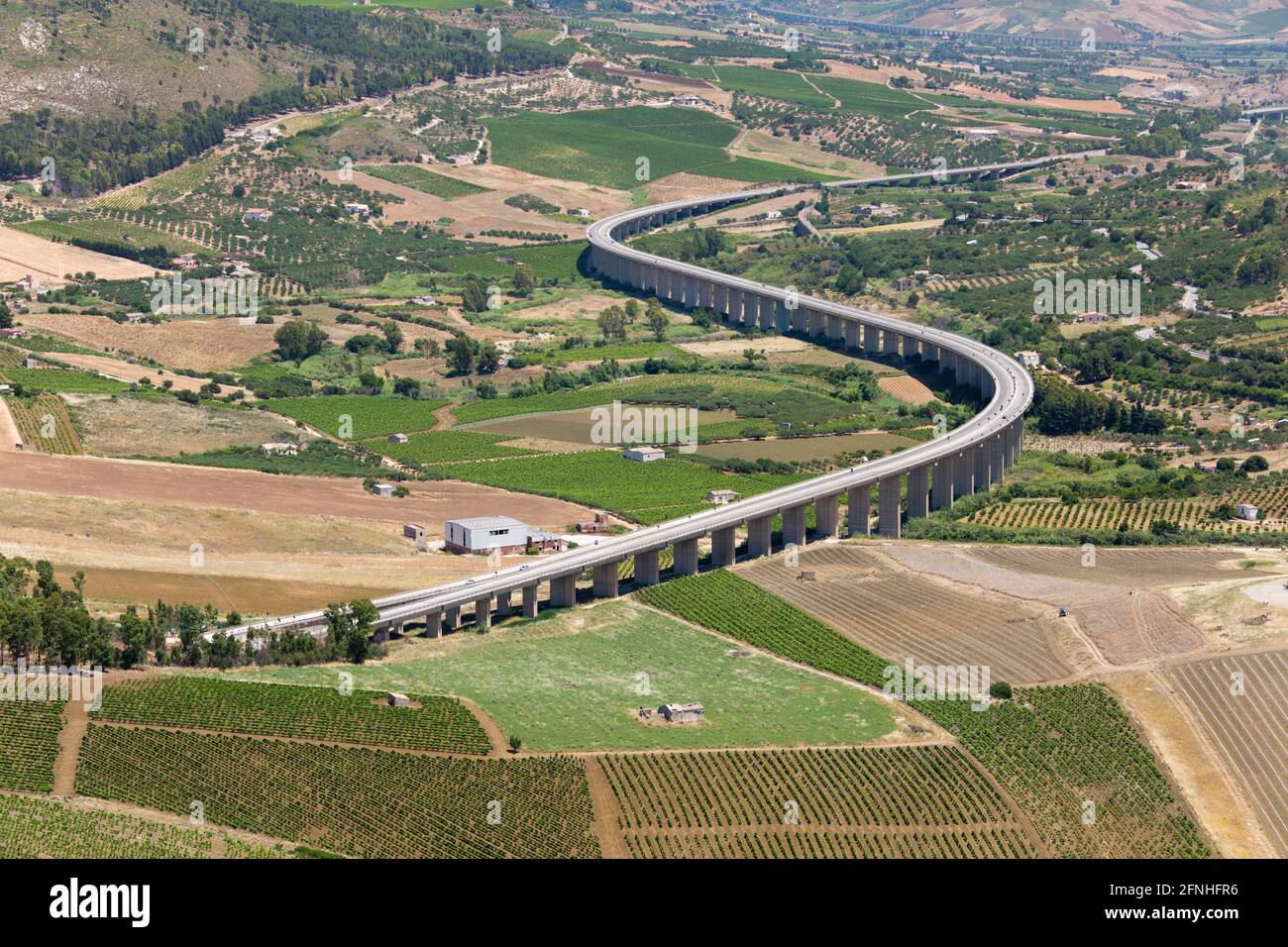 Calatafimi-Segesta, Trapani, Sizilien, Italien. Abgehängte Autobahn, die sich über attraktive Ackerflächen unterhalb des Monte Bàrbaro schlängelt, archäologische Stätte von Segesta. Stockfoto