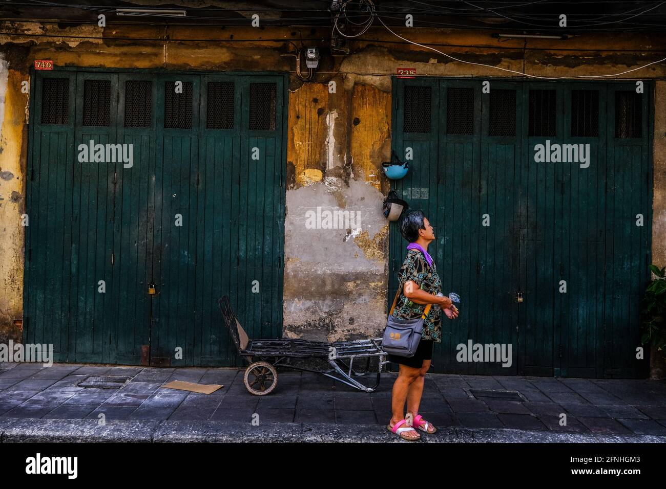 Eine Frau steht vor zwei alten grünen Türen in der Chinatown-Gegend von Bangkok, Thailand Stockfoto
