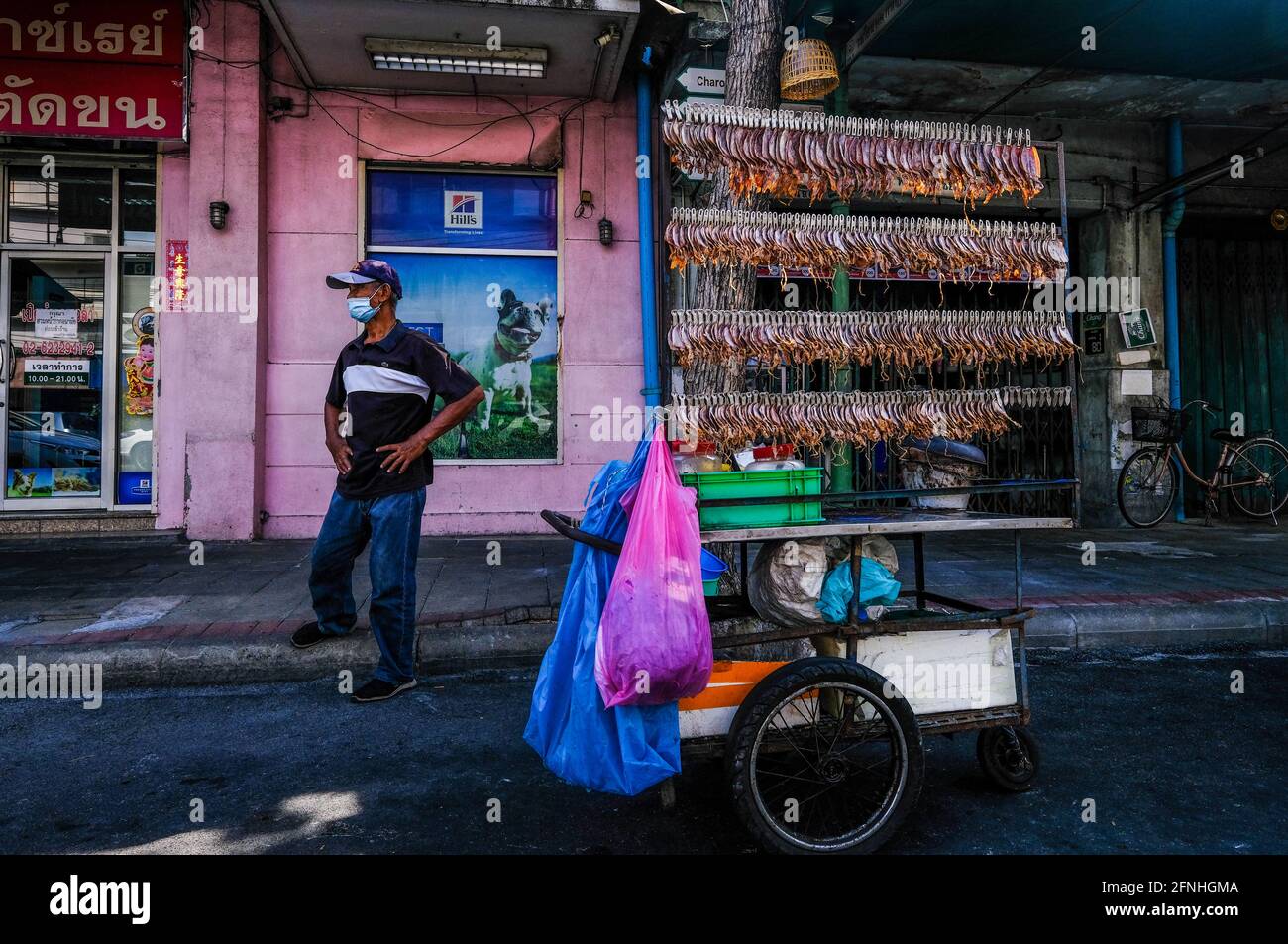 In Chinatown, Bangkok, Thailand, steht ein männlicher mobiler Händler von getrocknetem Fisch an seinem Wagen. Stockfoto