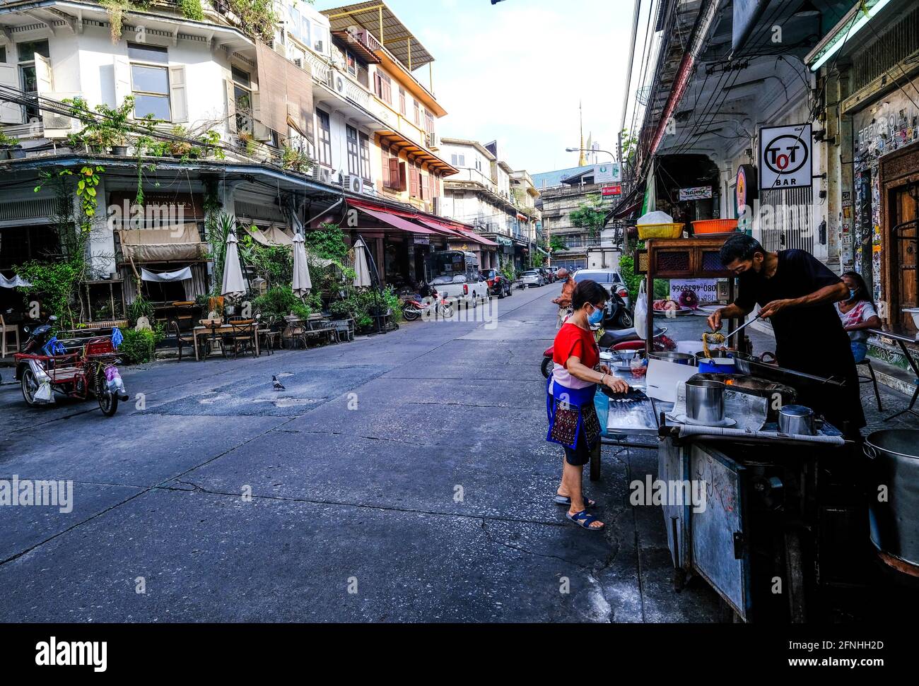 Ein männlicher Straßenverkäufer bereitet Speisen an einem Imbissstand im Freien in der Chinatown-Gegend von Bangkok, Thailand, zu Stockfoto