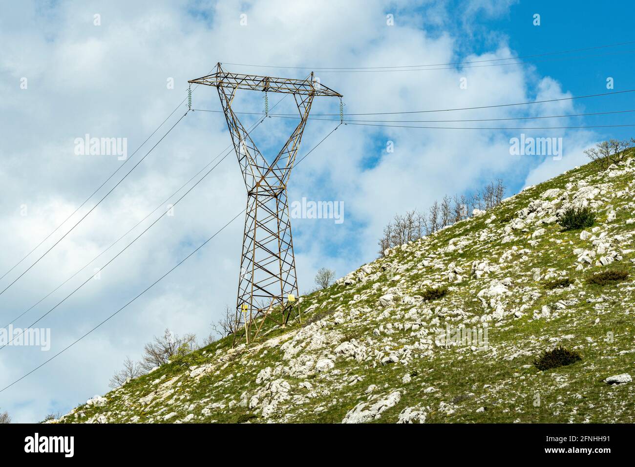 Mast der Hochspannungsleitung auf einem kargen Hügel. Abruzzen, Italien, Europa Stockfoto
