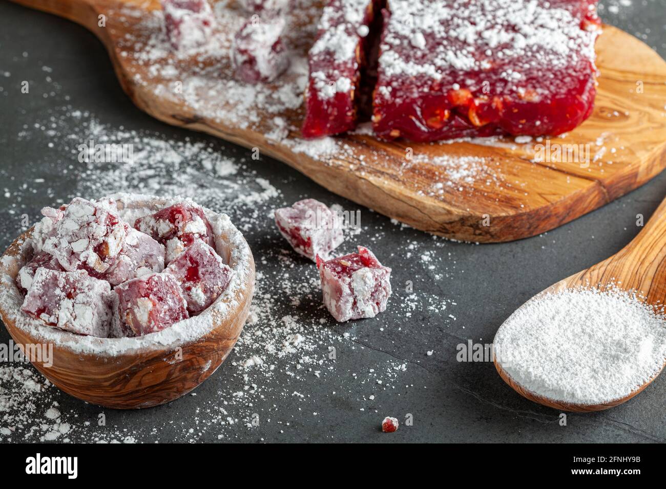 Herstellung von köstlichen Früchten aromatisierten hausgemachten türkischen Delight mit lebendigen rosa rote Farbe und gemischt mit Haselnüssen. Gesiebte Konditoren Zucker wird hinzugefügt Stockfoto