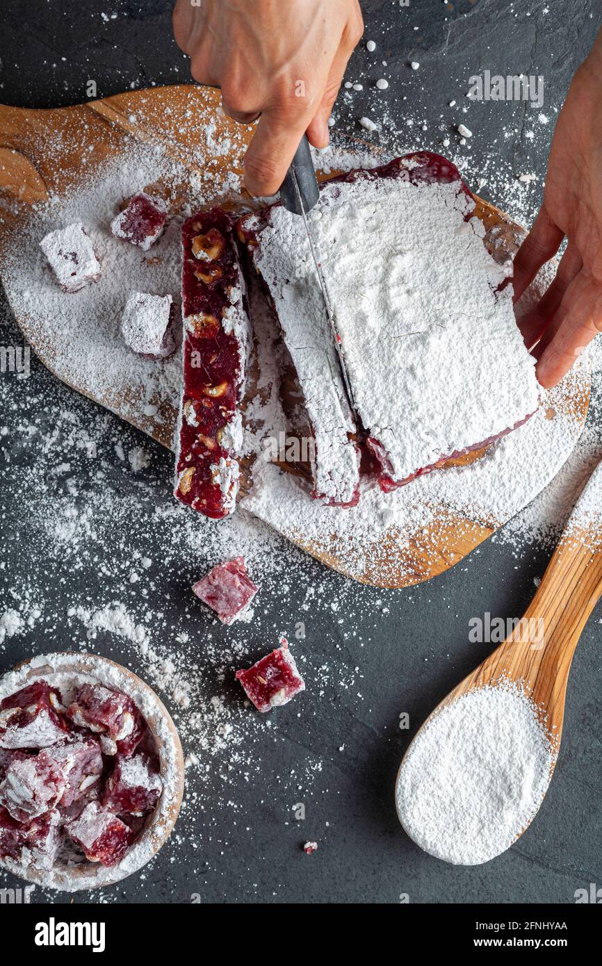 Herstellung von köstlichen Früchten aromatisierten hausgemachten türkischen Delight mit lebendigen rosa rote Farbe und gemischt mit Haselnüssen. Gesiebte Konditoren Zucker wird hinzugefügt Stockfoto