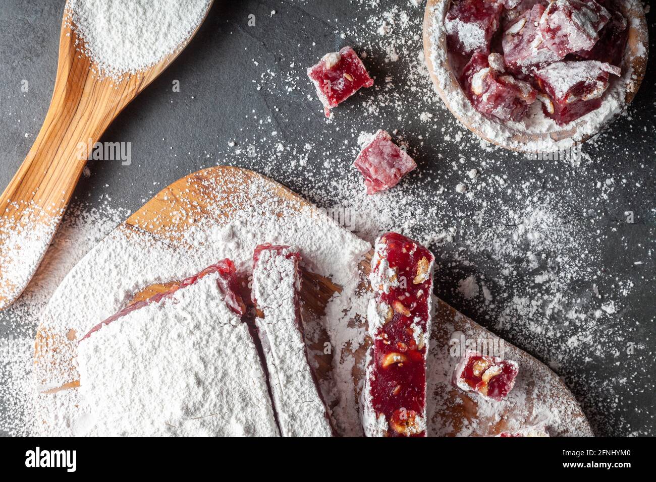 Herstellung von köstlichen Früchten aromatisierten hausgemachten türkischen Delight mit lebendigen rosa rote Farbe und gemischt mit Haselnüssen. Gesiebte Konditoren Zucker wird hinzugefügt Stockfoto