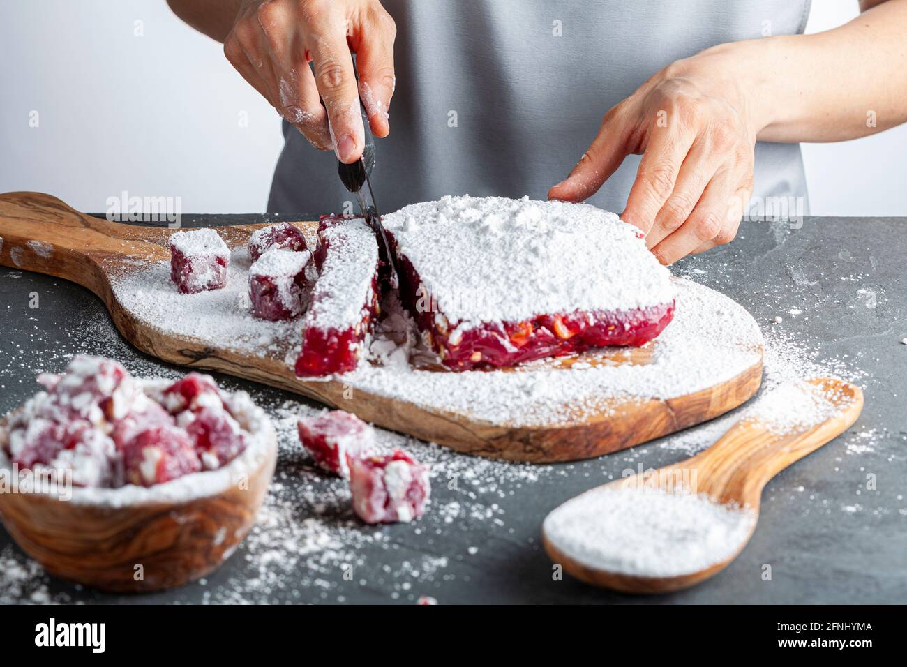 Herstellung von köstlichen Früchten aromatisierten hausgemachten türkischen Delight mit lebendigen rosa rote Farbe und gemischt mit Haselnüssen. Gesiebte Konditoren Zucker wird hinzugefügt Stockfoto