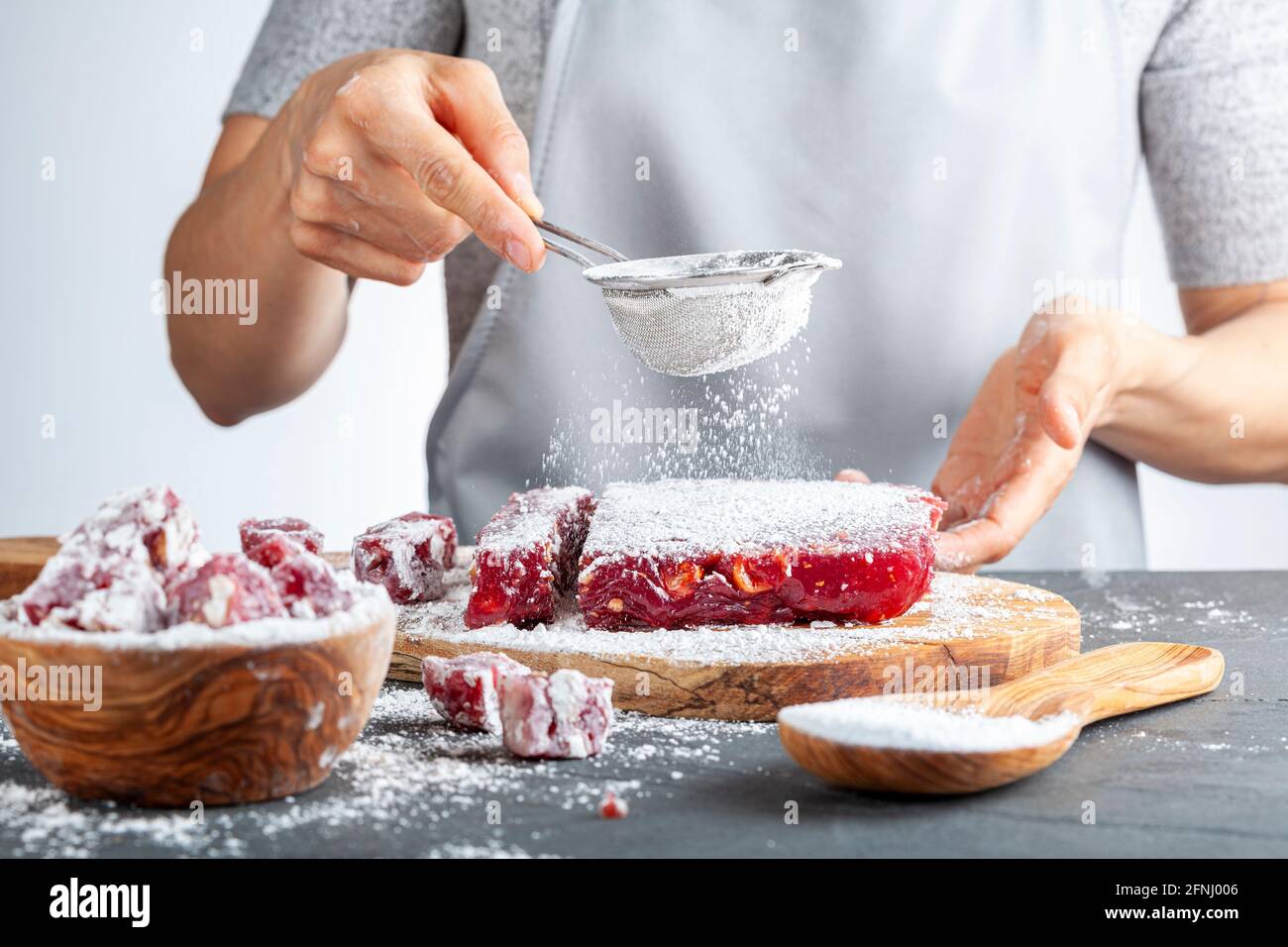 Herstellung von köstlichen Früchten aromatisierten hausgemachten türkischen Delight mit lebendigen rosa rote Farbe und gemischt mit Haselnüssen. Gesiebte Konditoren Zucker wird hinzugefügt Stockfoto