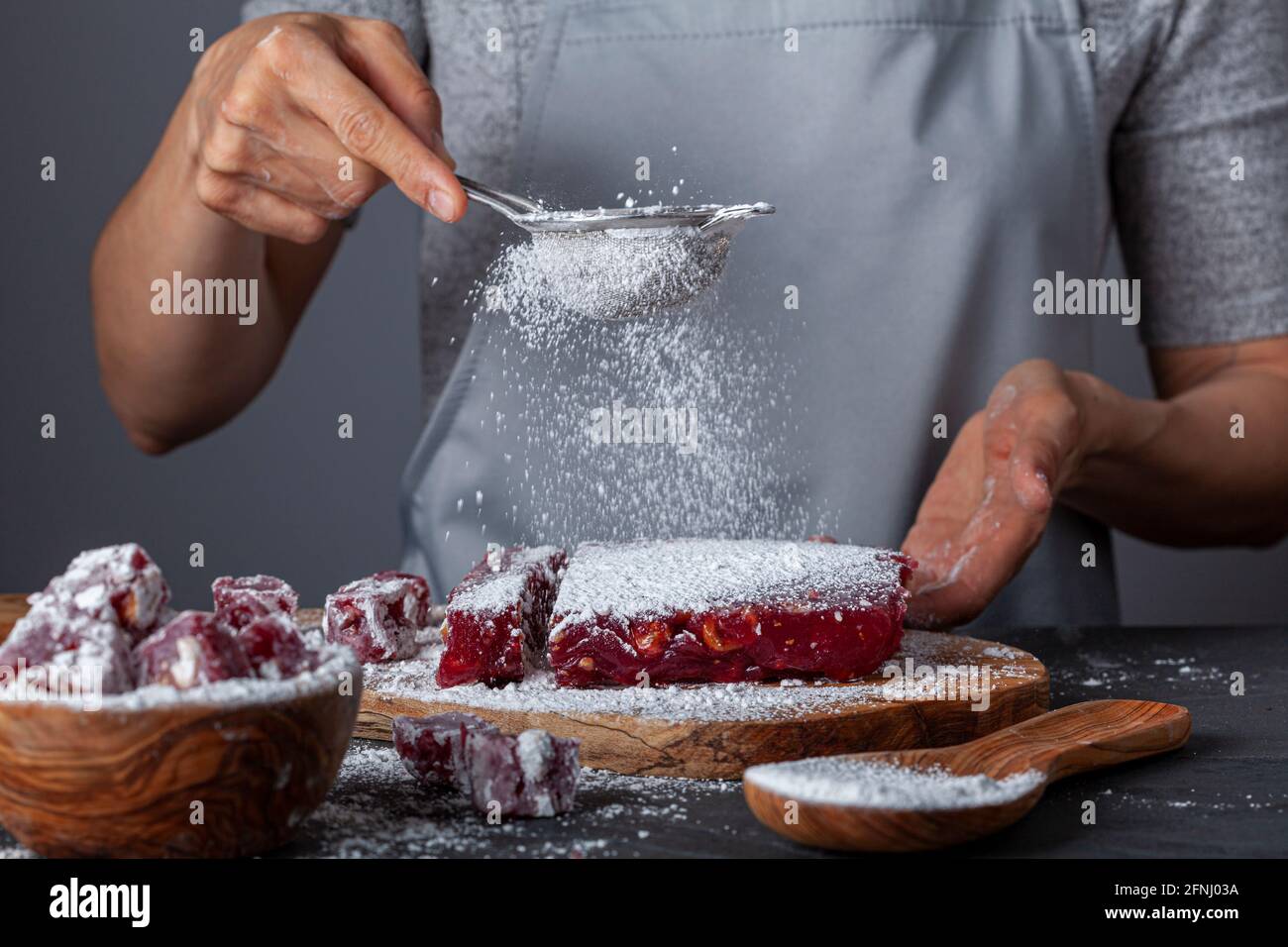 Herstellung von köstlichen Früchten aromatisierten hausgemachten türkischen Delight mit lebendigen rosa rote Farbe und gemischt mit Haselnüssen. Gesiebte Konditoren Zucker wird hinzugefügt Stockfoto