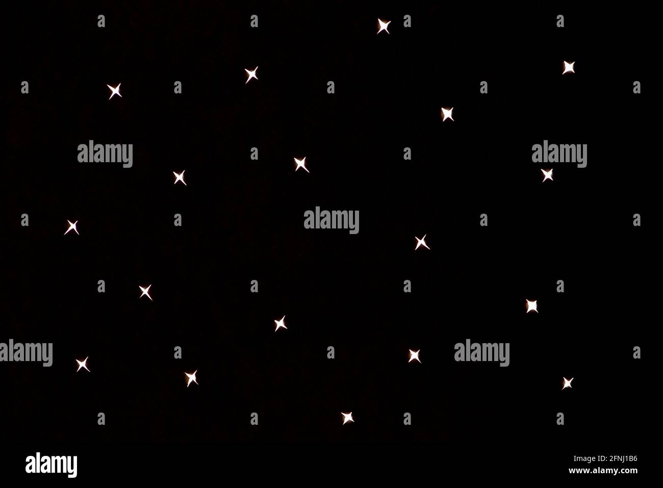 Zufällige kleine weiße sternförmige Punkte auf schwarzem Hintergrund. Minimalistischer Sternenhintergrund. Stockfoto