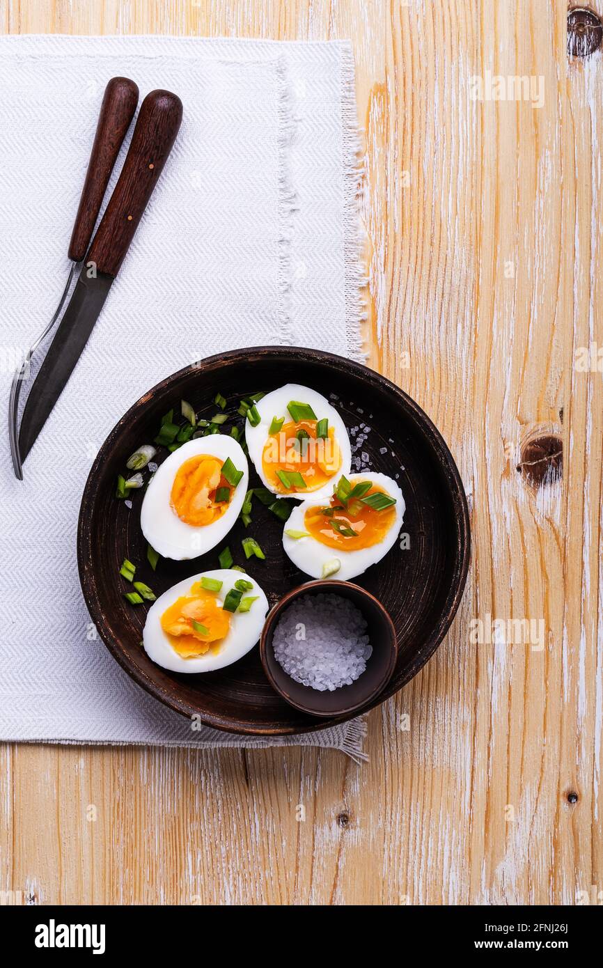 Halbierte hartgekochte Eier auf dem Teller auf einem rustikalen Holztisch, Draufsicht, Keto-Diät-Frühstück Stockfoto