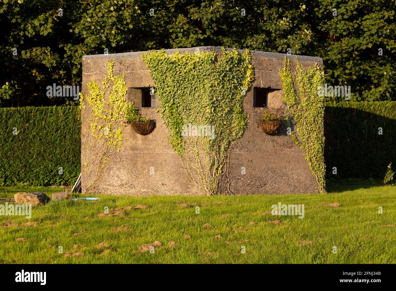 2. Weltkrieg Pillbox in der Nähe von Newton in Cartmel in Cumbria, England. Der Kriegsremanant hat Blumenkörbe und Reben auf seiner Betonfassade. Stockfoto