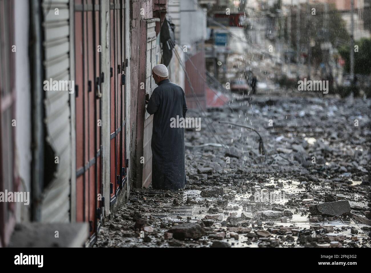 Gaza-Stadt, Palästinensische Gebiete. Mai 2021. Ein Palästinenser inspiziert die Überreste eines zerstörten Wohngebäudes in der Al-Wahda-Straße, nachdem es von israelischen Luftangriffen getroffen wurde, inmitten des eskalierenden Aufflackers der israelisch-palästinensischen Gewalt. Kredit: Mohammed Talatene/dpa/Alamy Live Nachrichten Stockfoto