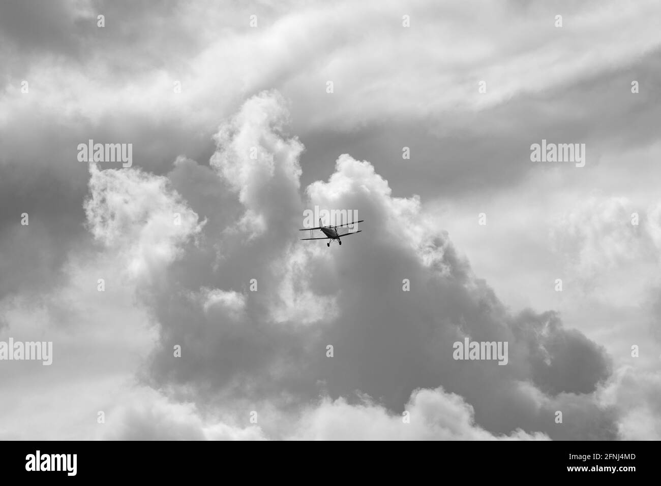 Monobild eines kleinen Doppelplanes hoch in der Luft Sie fliegen auf ein Wolkenmeer zu, das sich auftürmt Vorne und darüber Stockfoto
