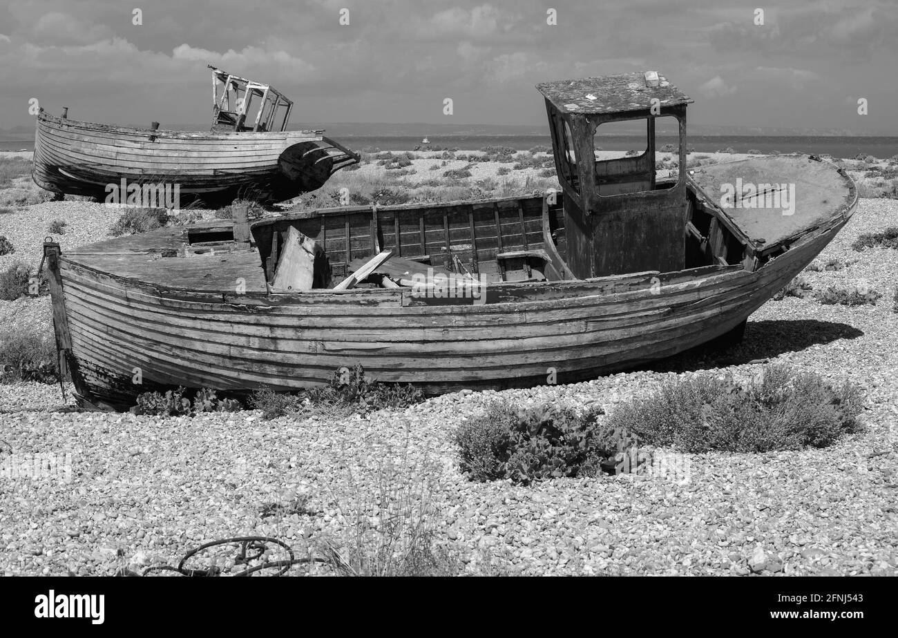 Monobild von zwei verfallenen, verlassenen und verfaulenden Fischerbooten an einem Kiesstrand Stockfoto