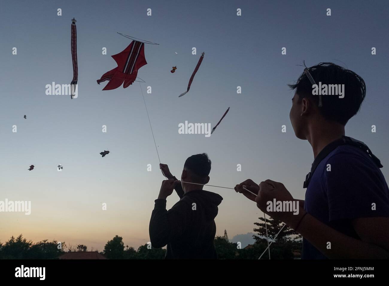 Denpasar, Bali, Indonesien. Mai 2021. Balinesische Jugendliche fliegen Drachen am Mertasari Beach, Sanur. Die Kitesaison findet jedes Jahr zwischen Mai und September während der Trockenzeit statt und ist die beste Zeit für einen Besuch im Tourismus auf Bali. Die Farben Rot, Weiß, Schwarz und Gold/Gelb repräsentieren die Inkarnationen der balinesischen Hindu-Gottheiten. Kredit: Dicky Bisinglasi/SOPA Images/ZUMA Wire/Alamy Live Nachrichten Stockfoto