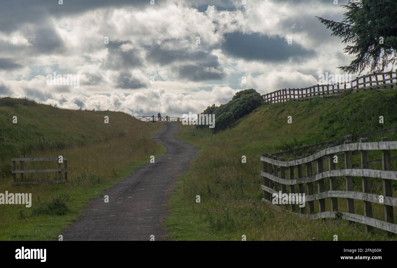 Blick auf den herannahenden Radfahrer auf dem kurvigen Pfad einer alten Eisenbahnstrecke, die heute ein öffentliches Vorfahrenrecht mit einem markanten Himmel in den Durham Dales ist Stockfoto