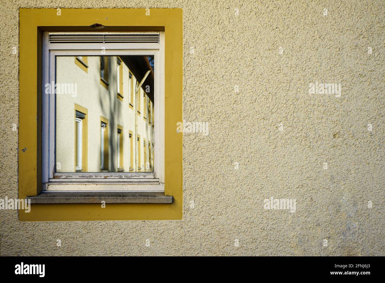 Bäume und Häuser spiegeln sich in der Mittagssonne in den Fenstern gegenüberliegender Häuser. Schöne Reflexe von Bäumen und Häusern. Stockfoto