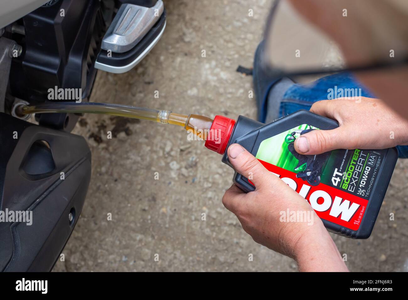 Anapa, Russland - 05.17.2021: Reparatur und Wartung eines Motorrads. Ölwechsel. Der Automechaniker gießt Motul-Öl über einen Gummischlauch in den Motor Stockfoto