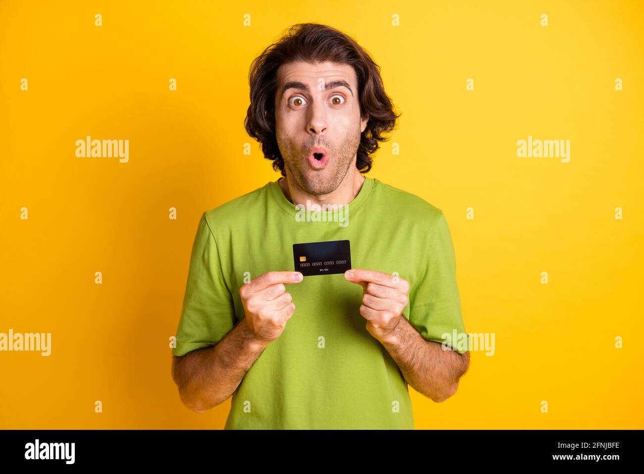 Porträtfoto eines schockierten Mannes, der eine Plastikkarte vorführt und anstarrt Isoliert auf lebhaft gelbem Hintergrund Stockfoto