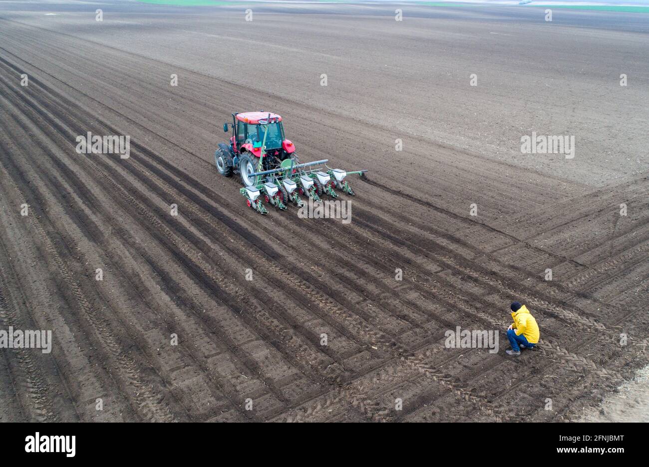 Luftbild des Landwirts, der den Traktor kontrolliert, der den Boden aussaat Drohne Stockfoto