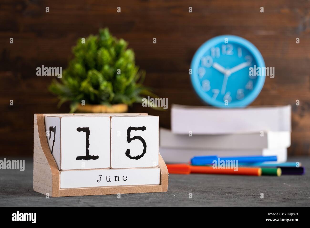 Juni. Juni 15 Holzwürfelkalender mit unscharfen Objekten auf dem Hintergrund. Stockfoto