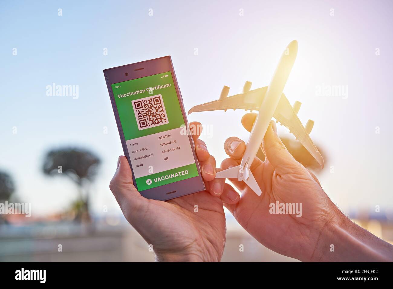 Smartphone zeigt auf App mobile gültigen digitalen grünen Impfpass für Covid-19 und Flugzeugspielzeug in der Hand. Immunitätsimpfstoff e-Pass, va Stockfoto