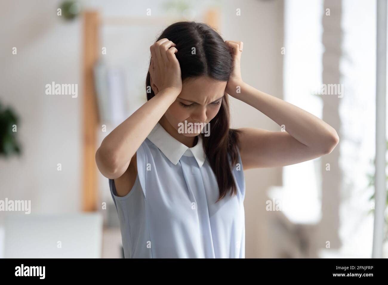 Unwohl junge Frau leidet an schweren Migräne am Arbeitsplatz Stockfoto