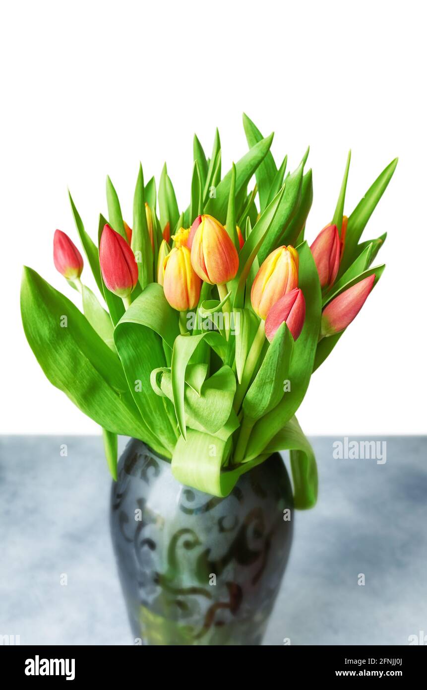 Tulpen mit Blättern in einer Vase auf weißem, selektivem Fokus. Stockfoto