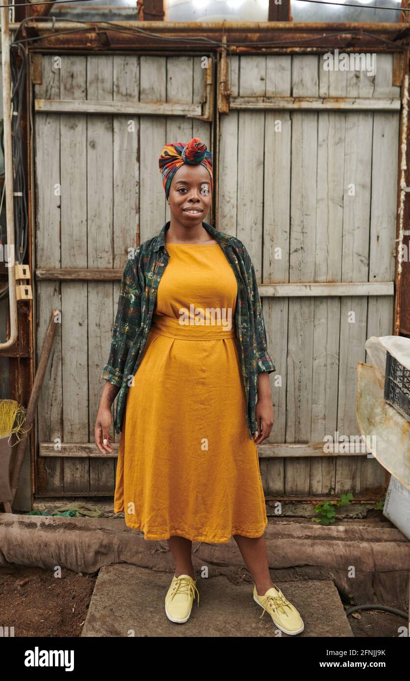 Porträt einer afrikanischen jungen Frau in schönen gelben Kleid lächelnd Bei der Kamera im Freien stehen Stockfoto