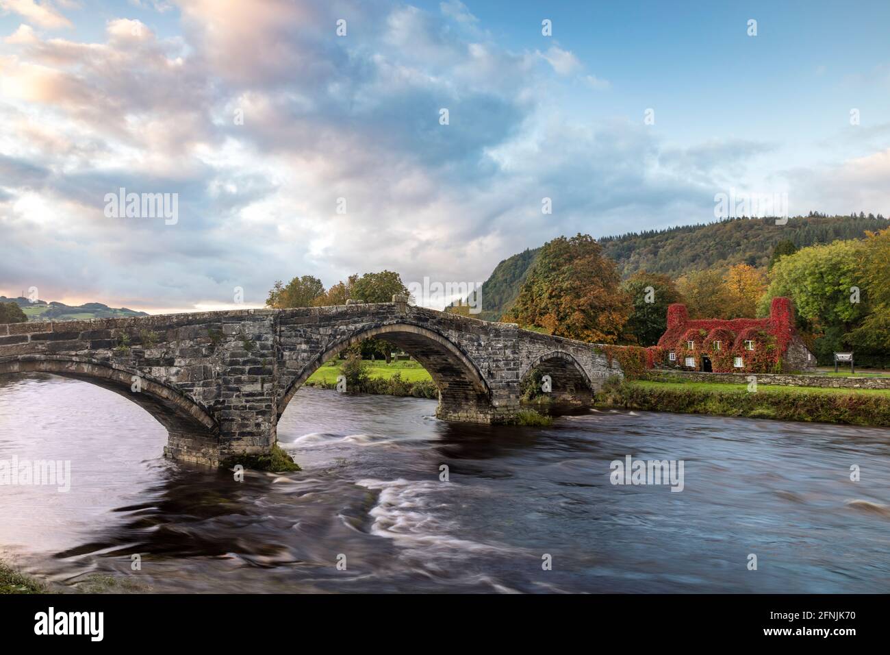 Der erste Morgengrauen über der Inigo Jones Bridge, dem Conwy River und dem TU Hwnt i’r Bont Tea Room, Llanwrst, Wales, Großbritannien Stockfoto