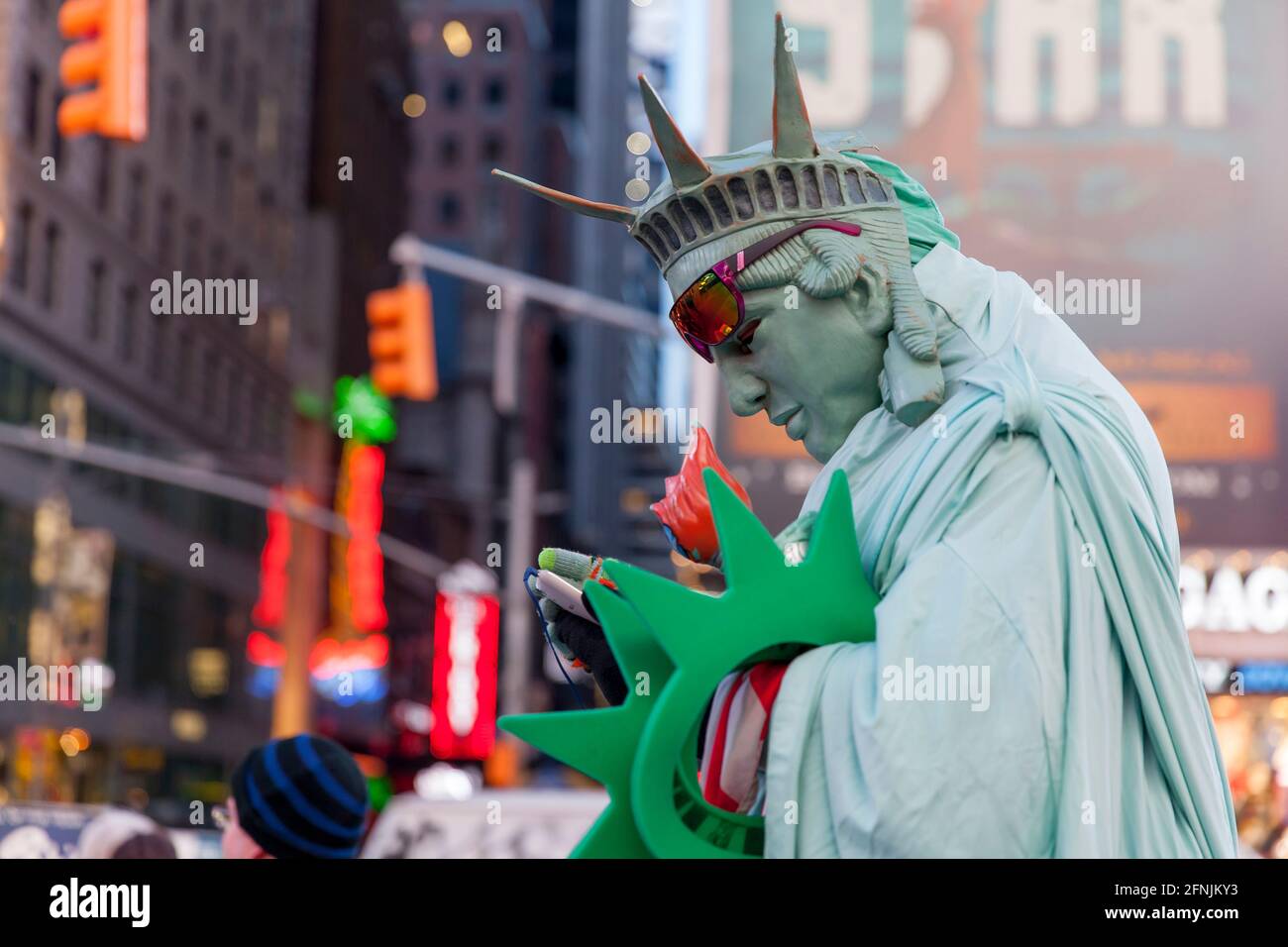 Mann in einem Kostüm der Freiheitsstatue beim Überprüfen des Mobiltelefons Stockfoto