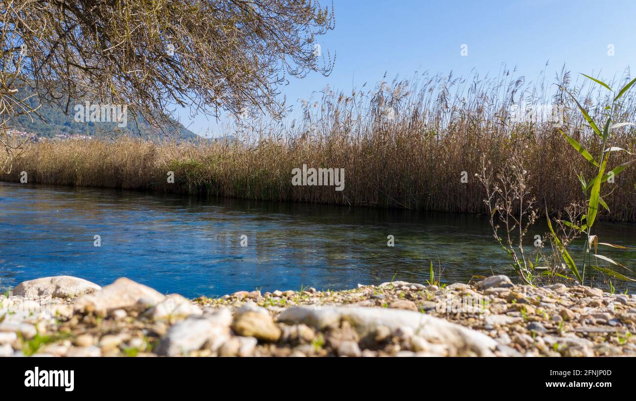 Ein schönes Panoramabild eines Sees neben einem Pfad voller Steine unter dem blauen Himmel. Diese realistische Aufnahme vermittelt die Schönheit von Mugla. Stockfoto